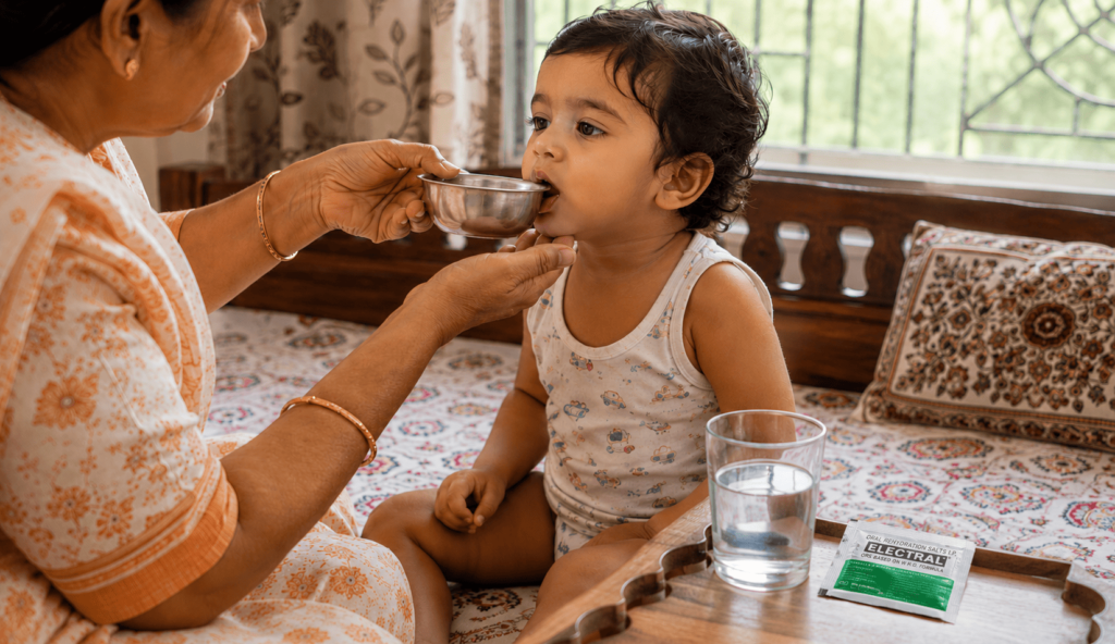 grandmother giving ORS solution to sick toddler